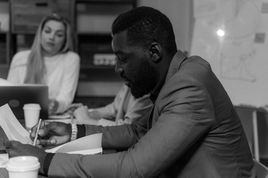 Focused businessman working in a monochrome office setting, collaborating with colleagues.